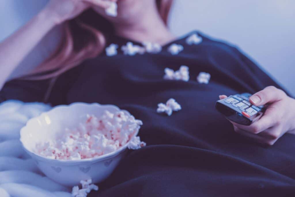 woman eating popcorn at night while watching tv